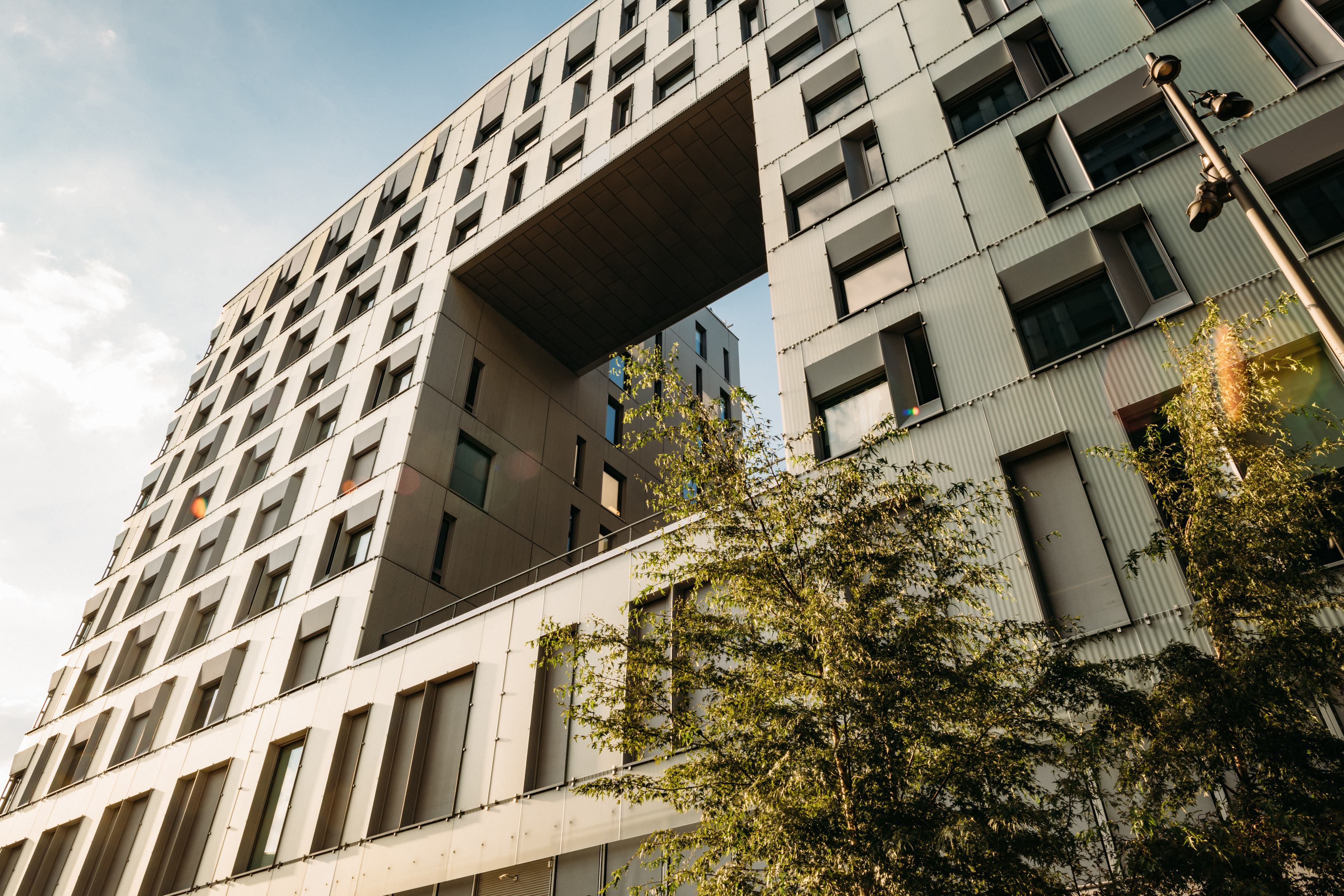 Close-up of the Diagonale building with a large rectangular cutout, windows, and trees in front.