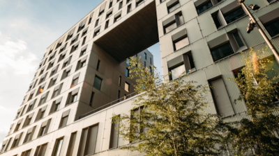 Närbild av Diagonale-byggnaden med stort rektangulärt utsnitt, fönster och träd framför.