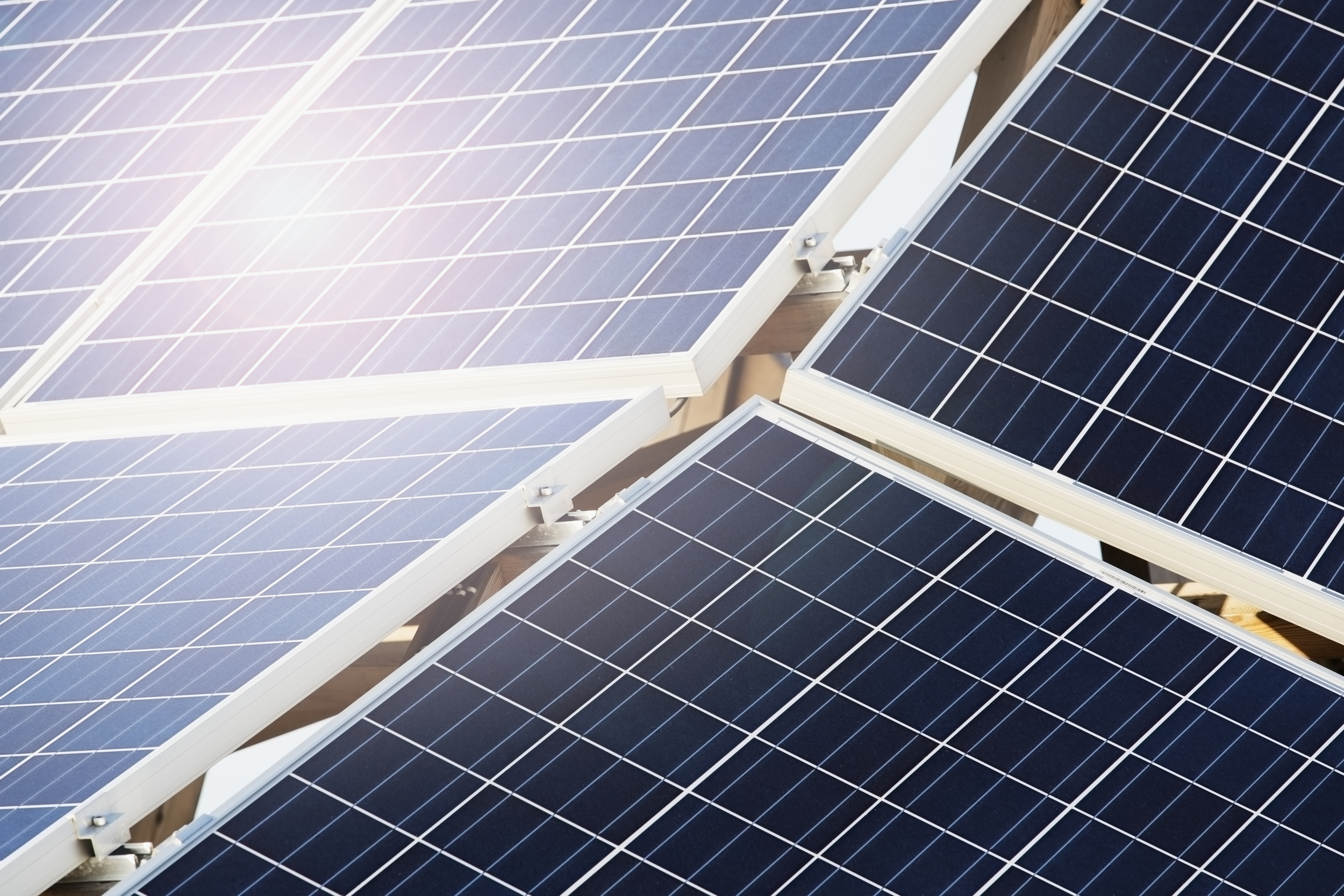 Närbild av solpaneler i ett rutnät som reflekterar solljus.